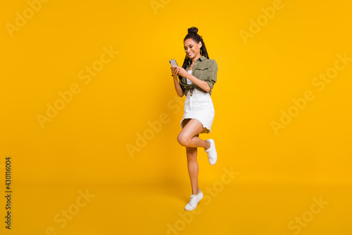 Full size profile photo of attractive dark skin person raise knee toothy smile isolated on yellow color background