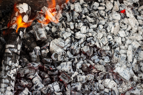 Burning coal in a barbecue. Beautiful texture of burnt firewood and coals in a campfire with bright fire for a barbecue close up © Dubnytskaya Photo