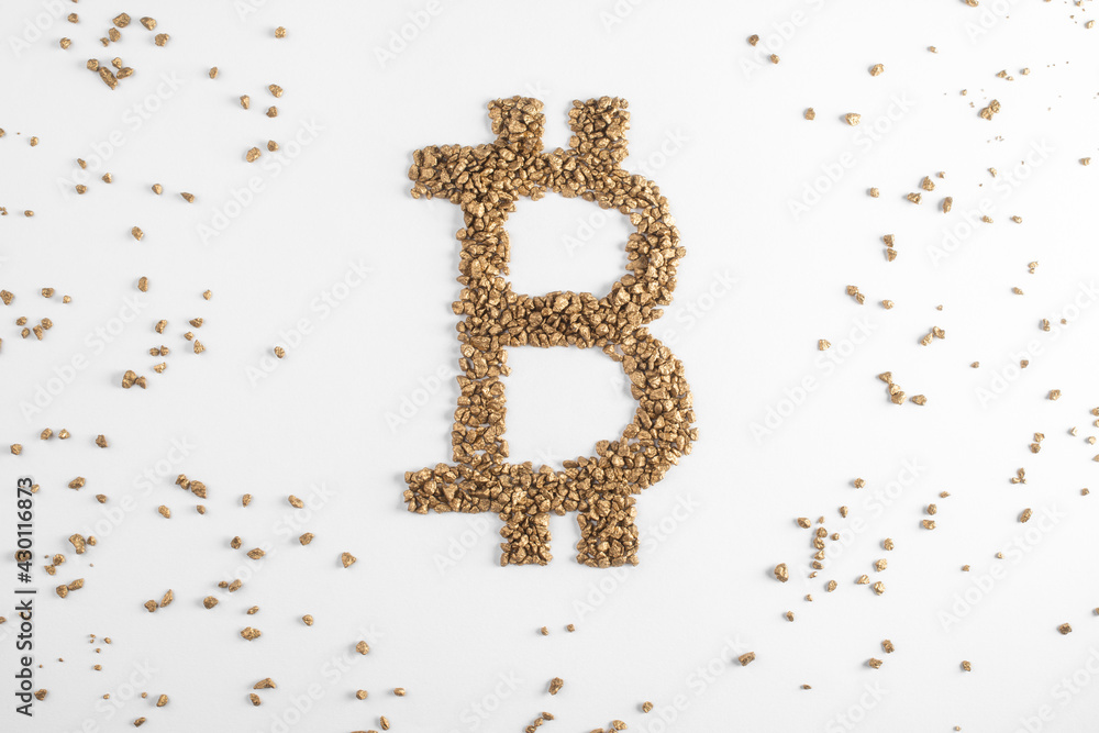 Top view on golden bitcoin sign surrounded with scattered pieces of gold Top view on golden bitcoin sign surrounded with scattered pieces of gold