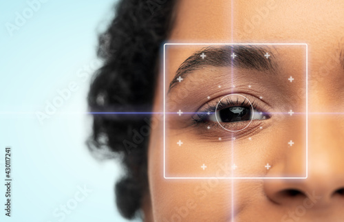 vision correction, laser eye surgery and health concept - close up of young african american woman face over blue background photo