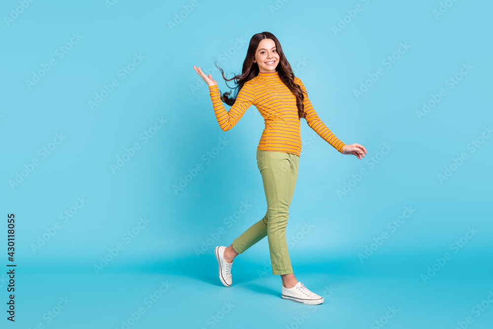 Full size profile photo of adorable friendly person walking hand throwing hair isolated on blue color background Full size profile photo of adorable friendly person walking hand throwing hair isolated on blue color background