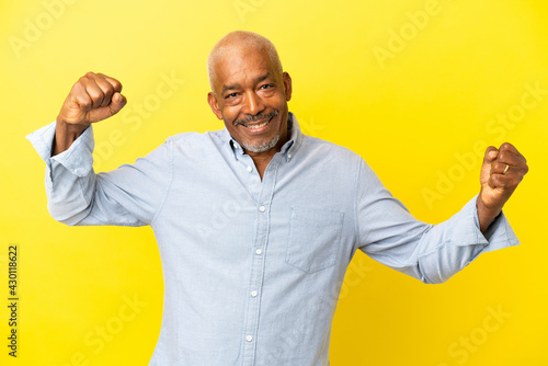 Cuban Senior isolated on yellow background doing strong gesture