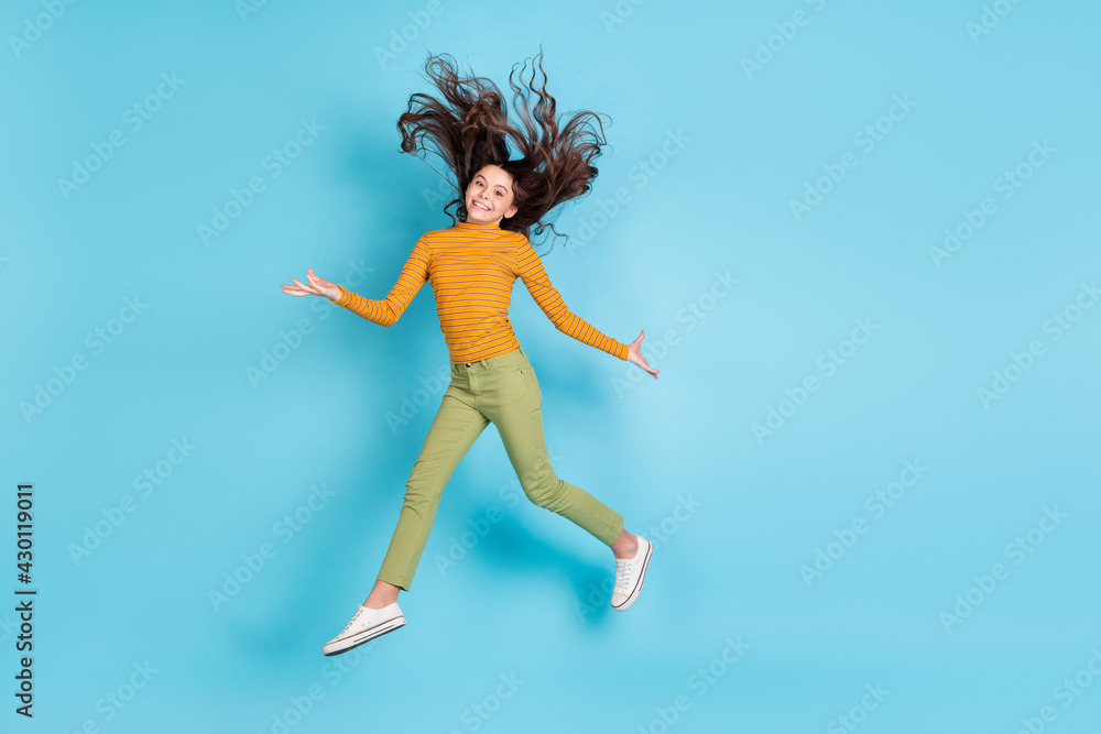 Full size portrait of charming cheerful girl toothy smile hair flying look camera isolated on blue color background Full size portrait of charming cheerful girl toothy smile hair flying look camera isolated on blue color background