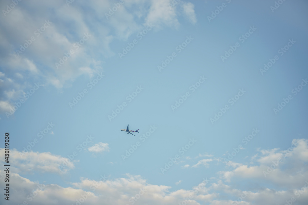 Fototapeta premium Airplane flying in the blue sky among clouds and sunlight