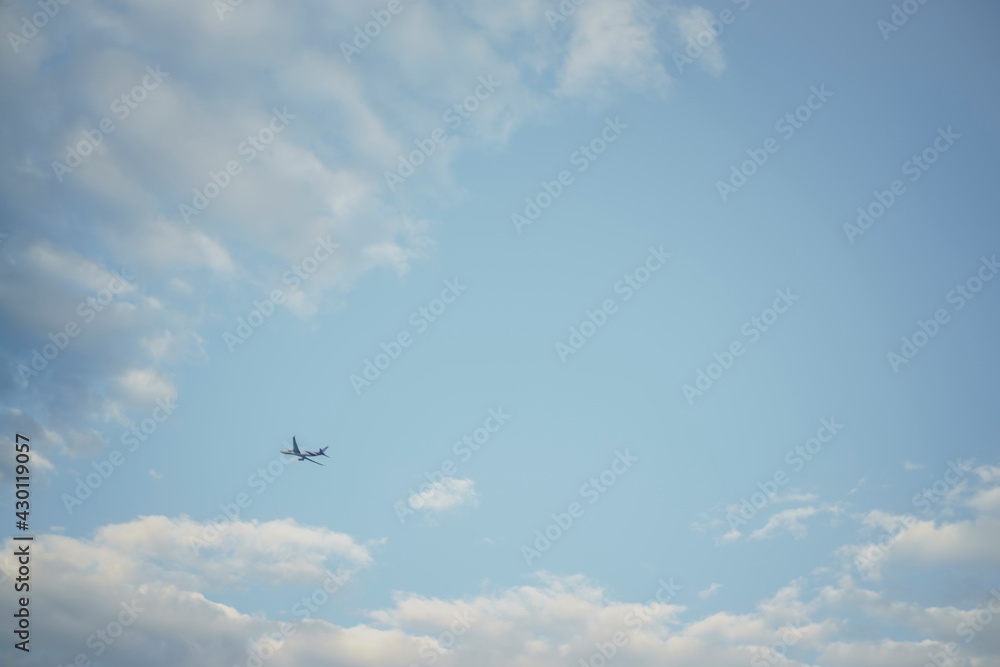 Airplane flying in the blue sky among clouds and sunlight