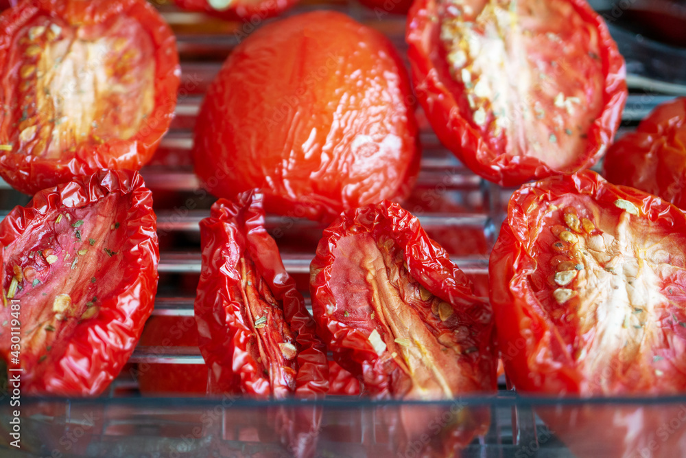 Tomatoes in the vegetable dryer. Dried tomatoes on the grill for drying. Tomatoes are greased with oil, seasoned with spices and dried Tomatoes in the vegetable dryer. Dried tomatoes on the grill for drying. Tomatoes are greased with oil, seasoned with spices and dried