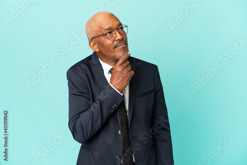 Business senior man isolated on blue background and looking up