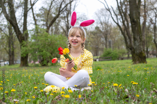 Happy Easter  adorable little girl wearing bunny ears lying on the grass outdoors