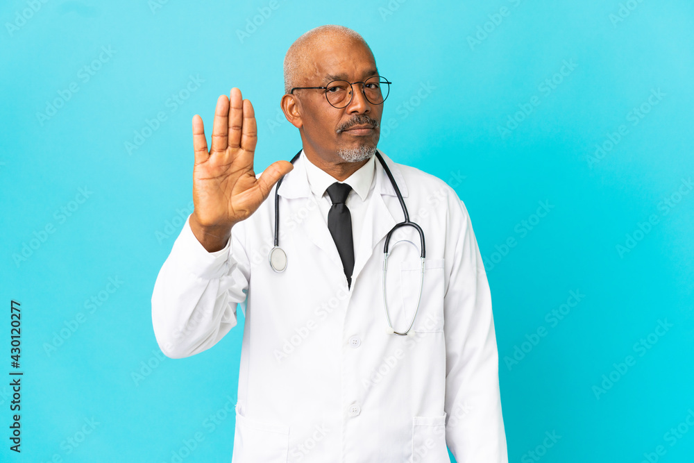 Senior doctor man isolated on blue background making stop gesture and disappointed Senior doctor man isolated on blue background making stop gesture and disappointed