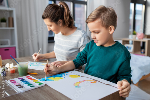 family, leisure and people concept - mother and little son with colors and paper drawing at home