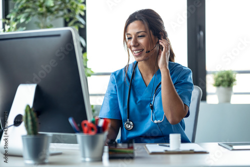 Wallpaper Mural Female doctor talking with earphone while explaining medical treatment to patient through a video call with computer in the consultation. Torontodigital.ca