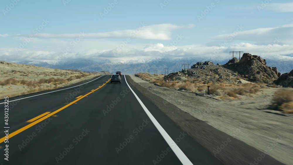 Road trip to Death Valley, driving auto in California, USA. Hitchhiking traveling in America. Highway, mountains and dry desert, arid climate wilderness. Passenger POV from car. Journey to Nevada.