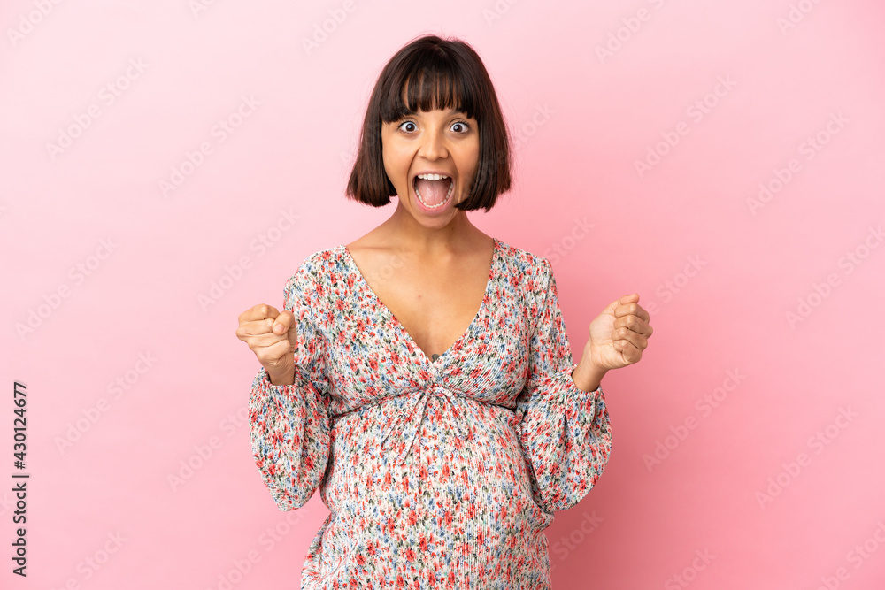 Young pregnant woman over isolated pink background celebrating a victory in winner position Young pregnant woman over isolated pink background celebrating a victory in winner position