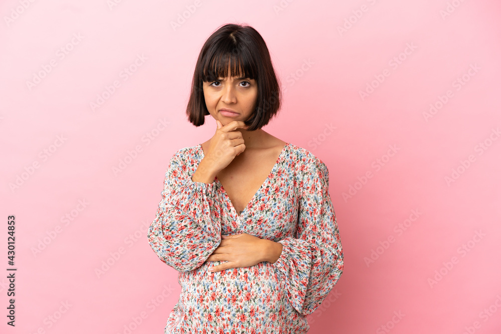 Young pregnant woman over isolated pink background having doubts Young pregnant woman over isolated pink background having doubts