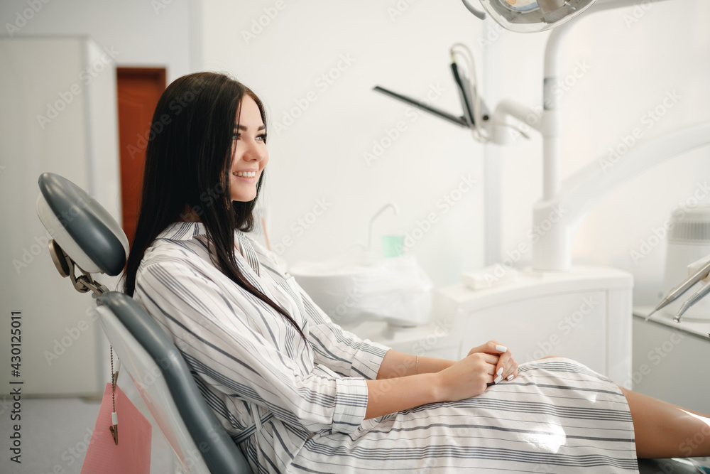 Smiling and satisfied patient in a dental office after treatment. Happy woman patient sitting on dentist chair in dental clinic. Dentistry care concept. Smiling and satisfied patient in a dental office after treatment. Happy woman patient sitting on dentist chair in dental clinic. Dentistry care concept.