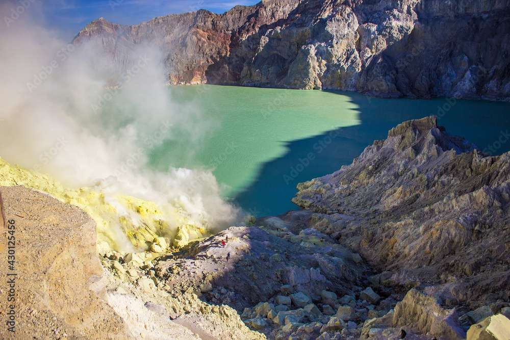 Beautiful sulfuric acid lake and gas coming out of the sulphur mines in the crater on the bottom of Mount Kawah Ijen active volcano, Banyuwangi, East Java, Indonesia. 