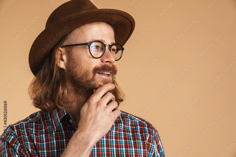 Smiling ginger man wearing eyeglasses and hat looking aside Smiling ginger man wearing eyeglasses and hat looking aside