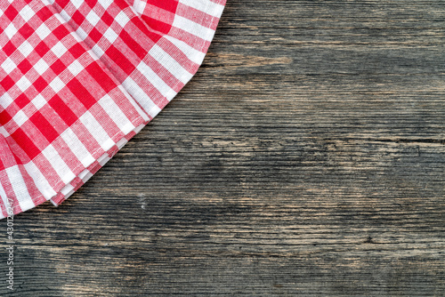 Red checkered towel on the kitchen table. Wooden table background.