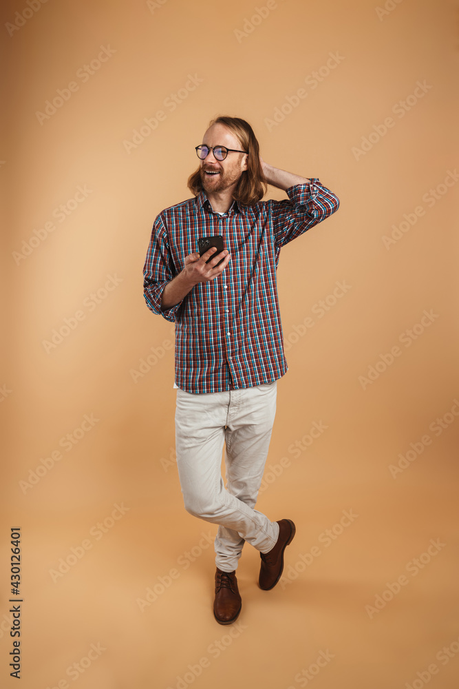 Fototapeta premium White ginger man wearing eyeglasses smiling and using cellphone