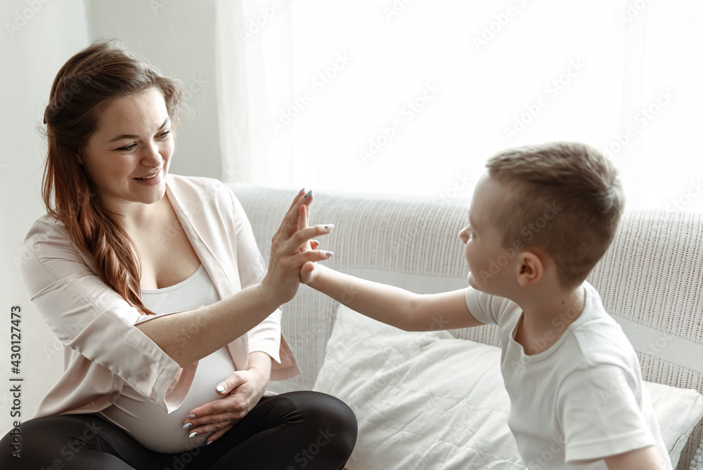 Young pregnant woman with her little son at home on the couch. Young pregnant woman with her little son at home on the couch.