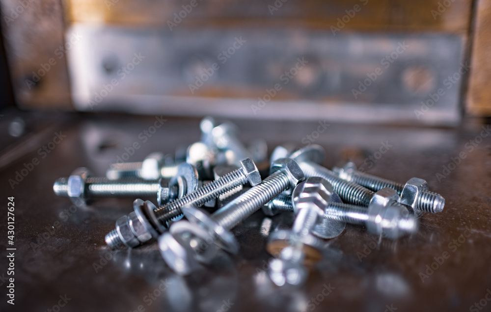 Metal chrome bolts and nuts lie on the shiny metal surface of the machine Metal chrome bolts and nuts lie on the shiny metal surface of the machine