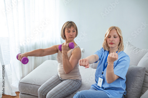 Physiotherapist woman giving exercise with dumbbell treatment About Arm and Shoulder of athlete female patient Physical therapy concept. Modern rehabilitation physiotherapy