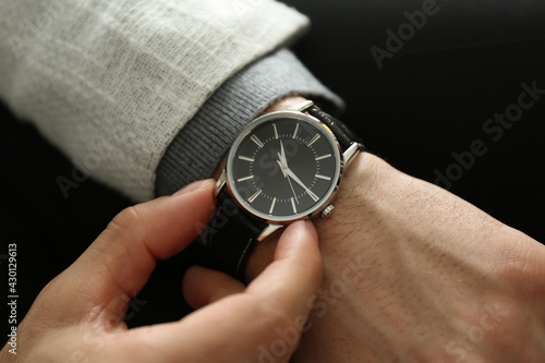 Businessman in jacket with luxury wrist watch on black background, closeup