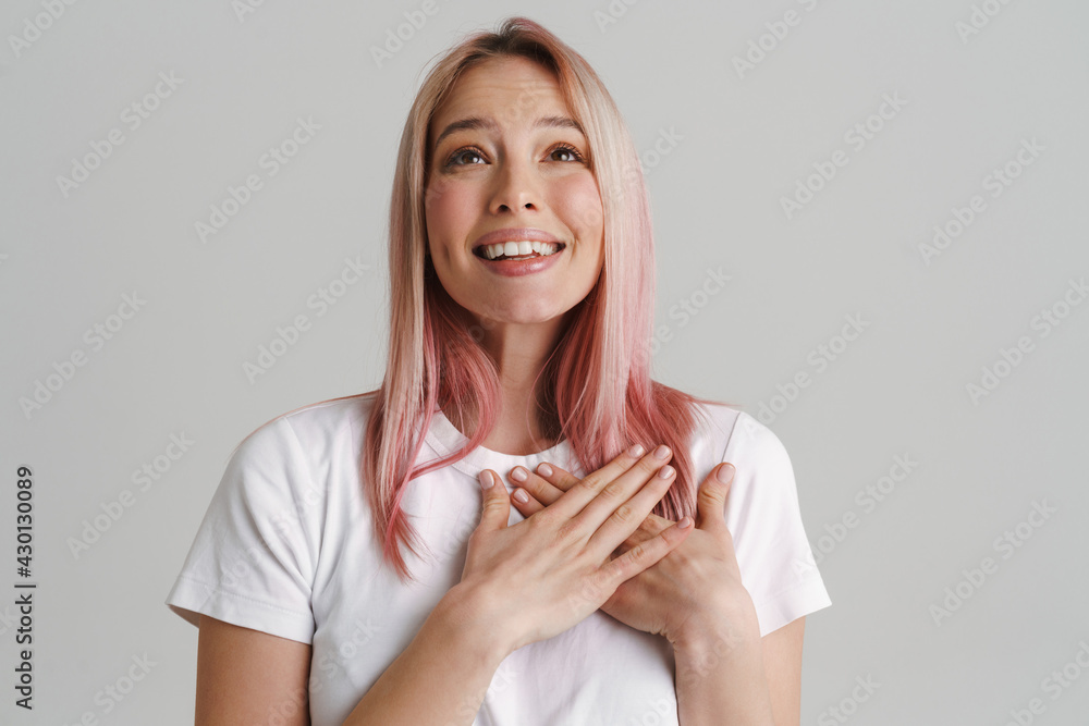 Young woman with pink hair smiling while holding hands on her chest Young woman with pink hair smiling while holding hands on her chest