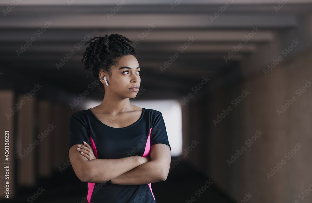 Portrait of young, athletic and attractive african american woman in sportswear and wireless headphones