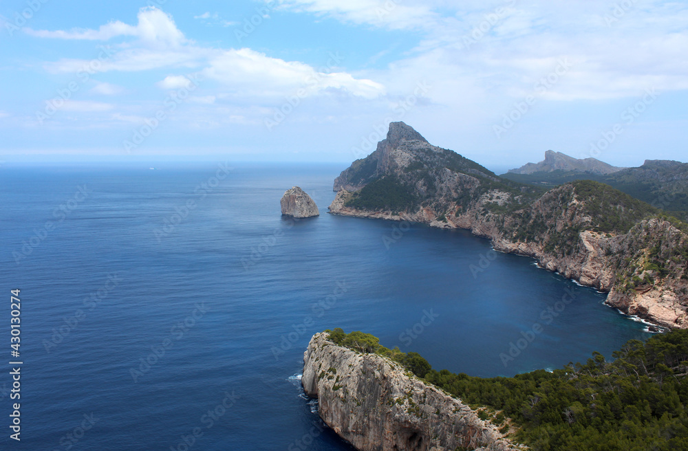 Beautiful natural landscape with a rocky headland, calm sea and cloudy skies. Mallorca, Balearic Islands, Spain