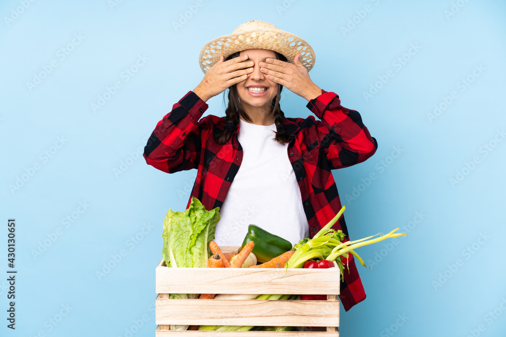 Young farmer Woman holding fresh vegetables in a wooden basket covering eyes by hands