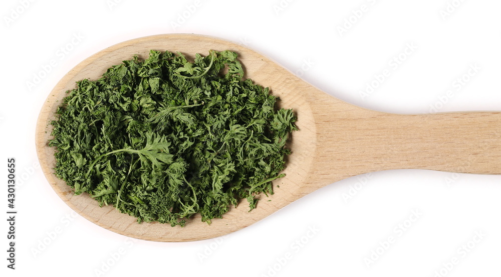 Dried and sliced French parsley leaves with wooden spoon isolated on white background, top view Dried and sliced French parsley leaves with wooden spoon isolated on white background, top view