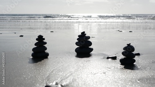 Rock balancing on ocean beach  stones stacking by sea water waves. Pyramid of pebbles on sandy shore. Stable pile or heap in soft focus with bokeh  close up. Seamless looped cinemagraph. Zen balance.