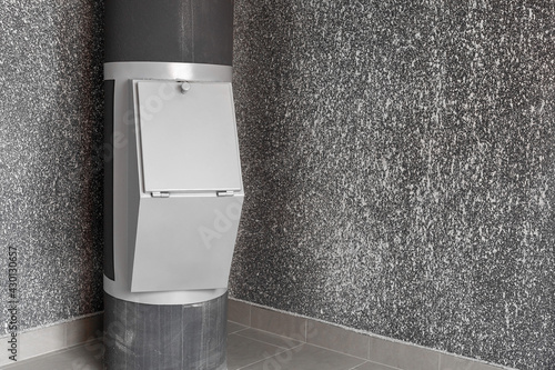Waste disposal container installed on the floor of a multi-storey building on the grey background. Cleaning and maintenance concept trash and linen and chute systems. Copy space.