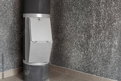 Waste disposal container installed on the floor of a multi-storey building on the grey background. Cleaning and maintenance concept trash and linen and chute systems. Copy space.