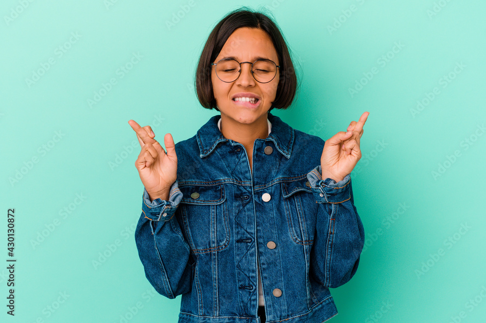 Young mixed race woman isolated on blue background crossing fingers for having luck Young mixed race woman isolated on blue background crossing fingers for having luck