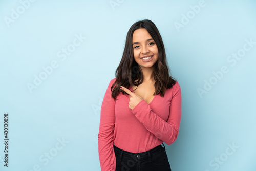 Young mixed race woman isolated on blue background pointing to the side to present a product © luismolinero