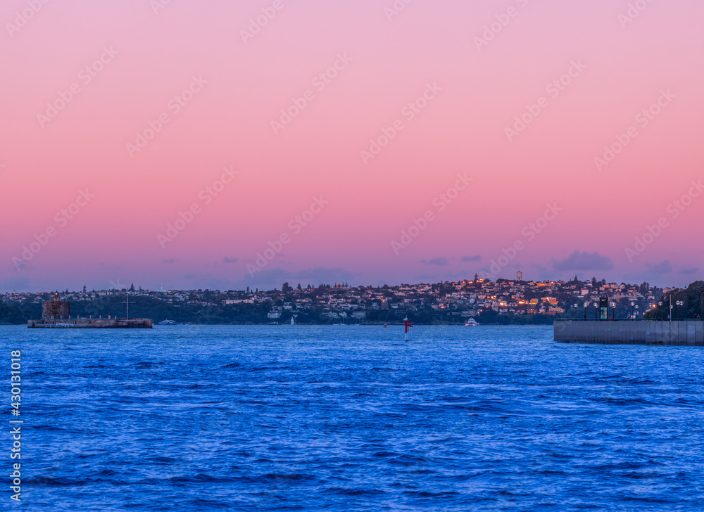 Residential apartment buildings on Sydney Harbour at sunset orange pink skies and building windows NSW Australia 