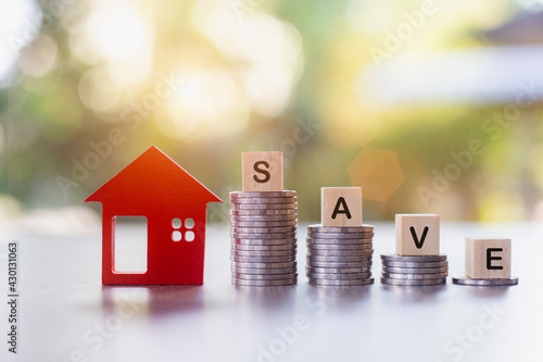 Savings. Investing in real estate. Graph of the growth of a pile of silver coins and a red wooden house. Loans to buy a home. Wooden letters blocks writing words notes Save for the future.