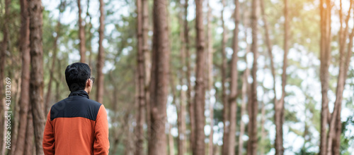 Happy traveler man standing and looking Pine tree forest, solo tourist in orange sweater traveling at Pang Oung, Mae Hong Son, Thailand. travel, trip and vacation concept