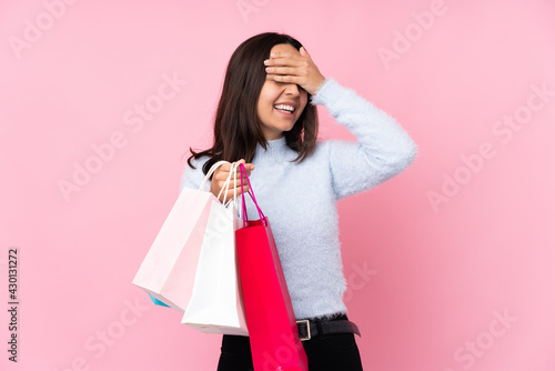 Young woman with shopping bag over isolated pink background smiling a lot