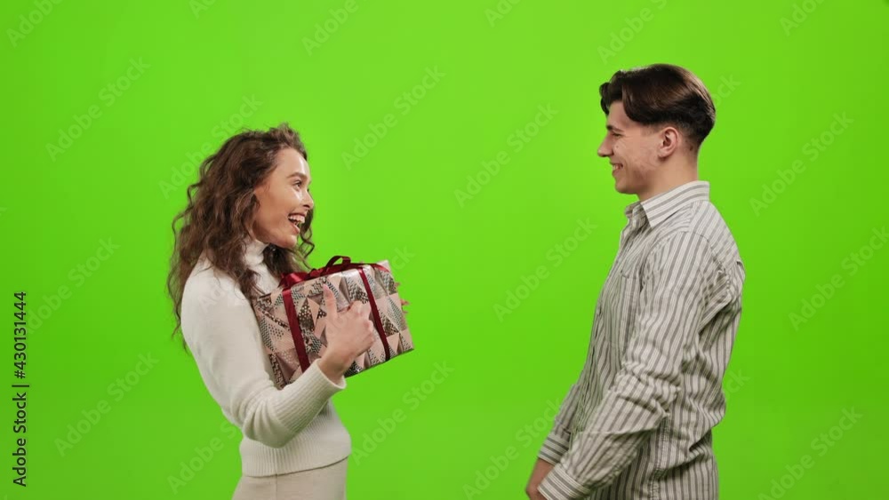 A man is giving a gift to a woman. She is very happy and smiles. They are embracing. They are standing on a green background. Green screen. 4K A man is giving a gift to a woman. She is very happy and smiles. They are embracing. They are standing on a green background. Green screen. 4K