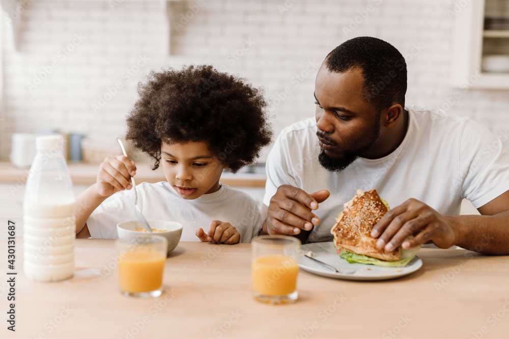 Black father and son having breakfast while sitting at table