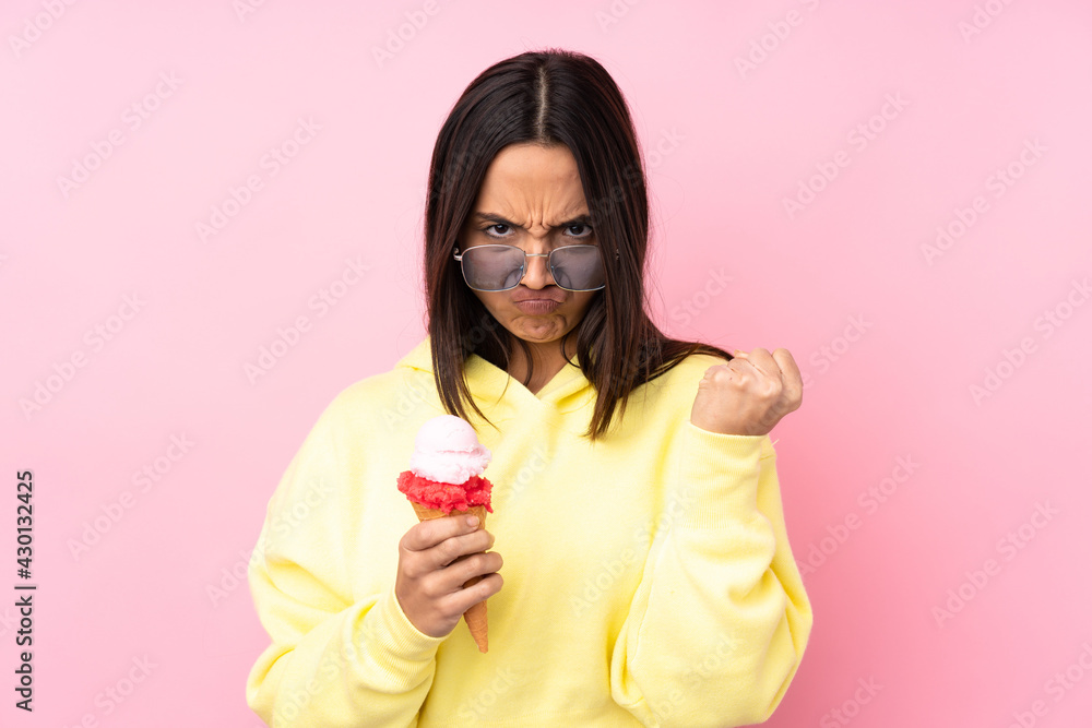Young brunette girl holding a cornet ice cream over isolated pink background with angry gesture Young brunette girl holding a cornet ice cream over isolated pink background with angry gesture