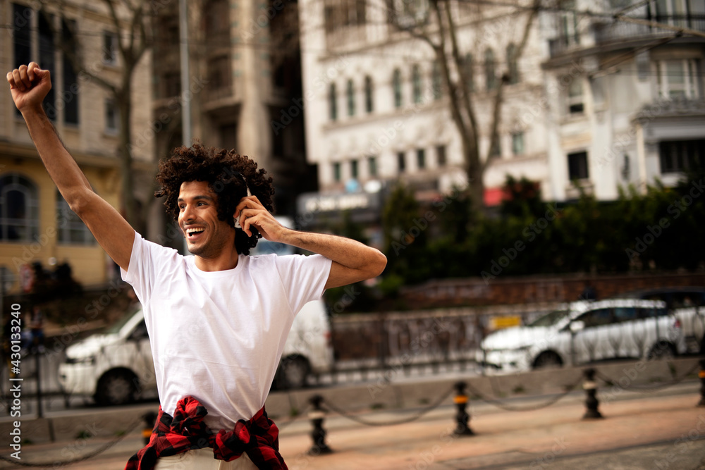 Obraz premium Young man outdoors. Handsome man listening music while walking through the city.
