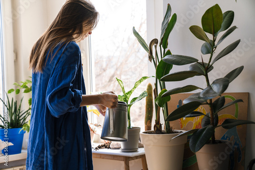 Obraz na plátne Young woman florist taking care of pot plants