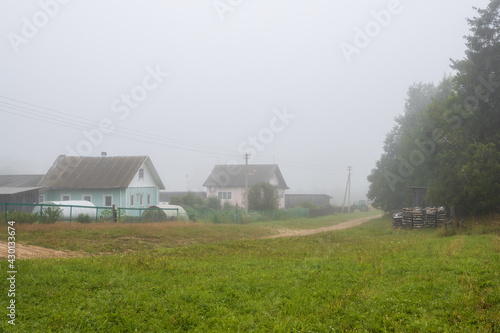 Misty rural landscape. Foggy morning in the countryside. View of a deserted village street and wooden houses in the fog. Summer in the village. Everyday life in the countryside. Vologda region  Russia
