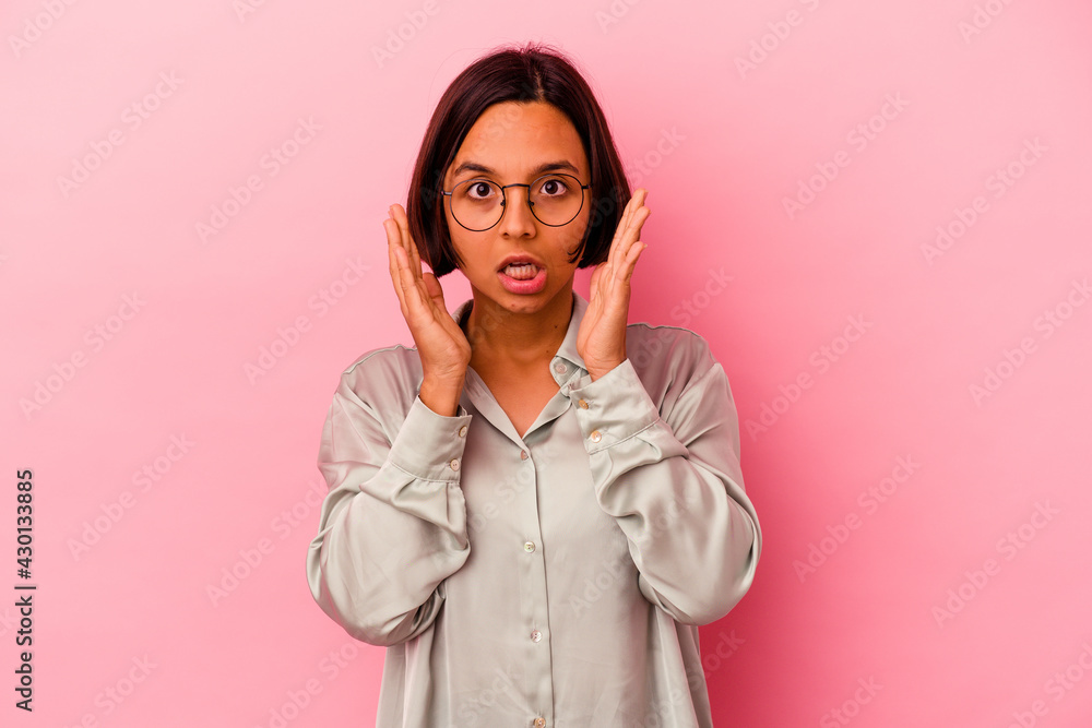 Young mixed race woman isolated on pink background surprised and shocked.