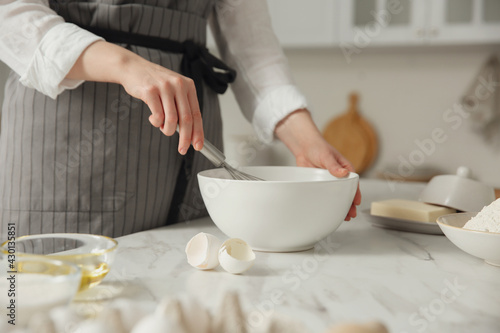 Woman making dough at table in kitchen, closeup