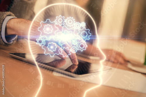 Double exposure of man and woman working together holding and using a mobile device and brain hologram drawing.